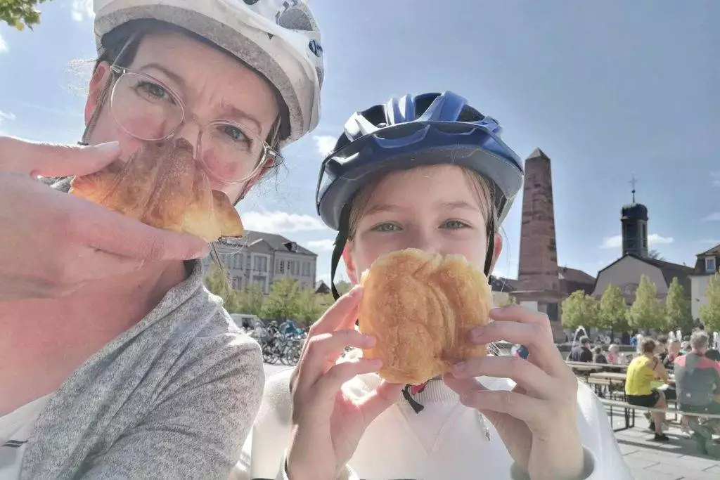 Vera mit Kind hält sich ein Croissant vor die Nase